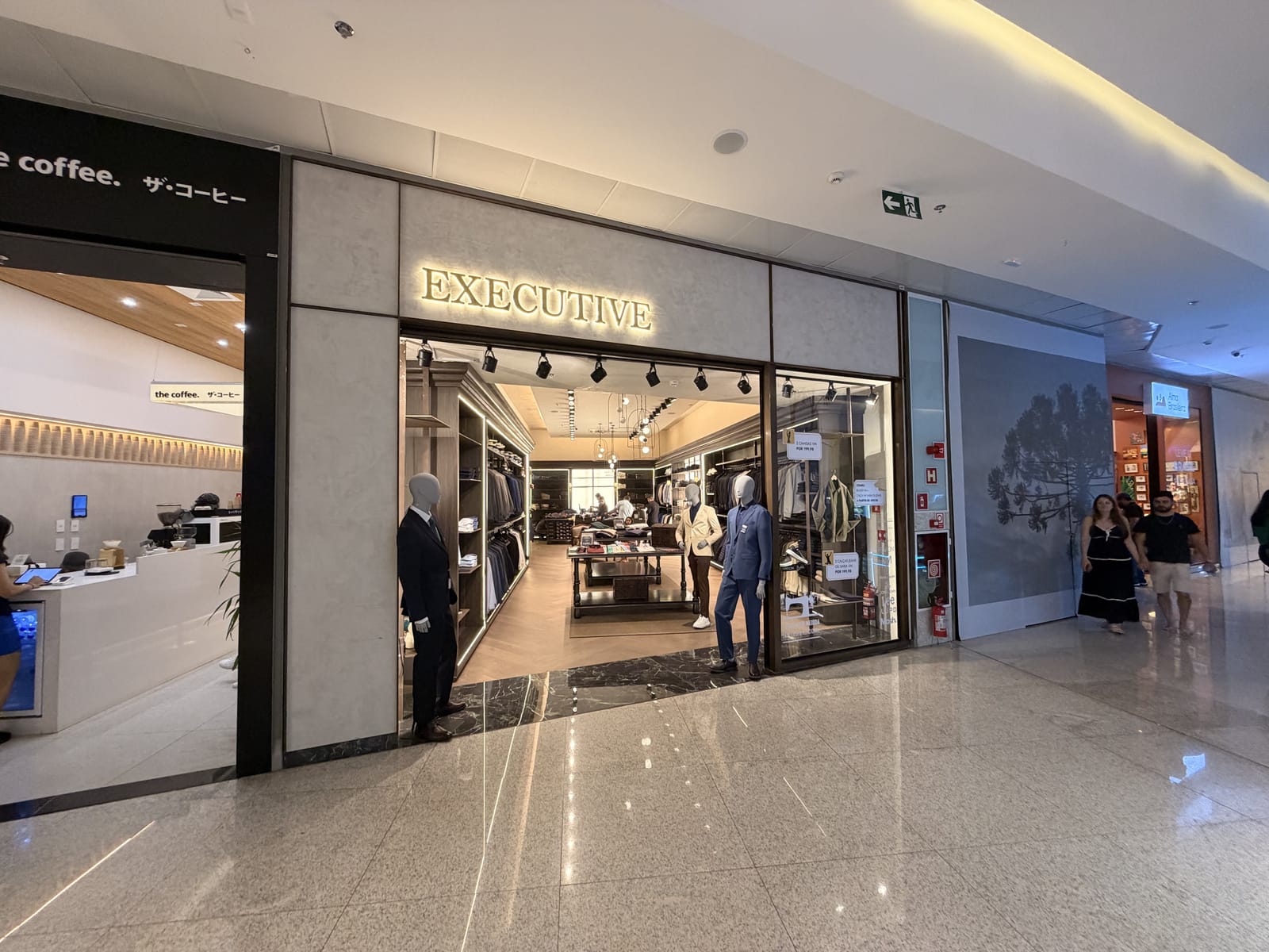 Loja Executive em shopping, fachada iluminada e interior com marcenaria e iluminação de destaque