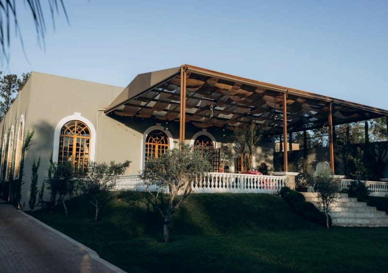 Fachada do espaço de eventos Fontana Di Fiori, com pedra natural, fonte ornamental e jardim